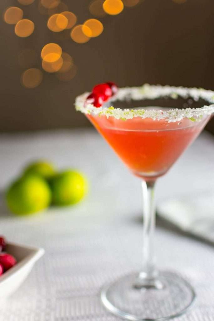 Cranberry sidecar in a martini glass that has rim decorated with sugar and lime zest.