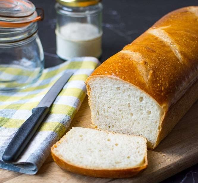 A slice of sourdough sandwich bread cut on a cutting board.