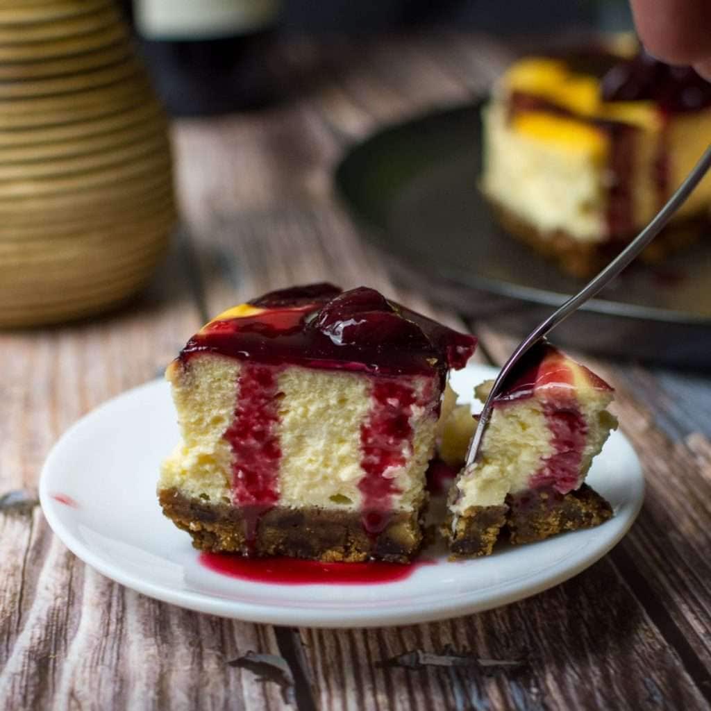 A slice of baked cherry cheesecake with cherries on top on a white plate.