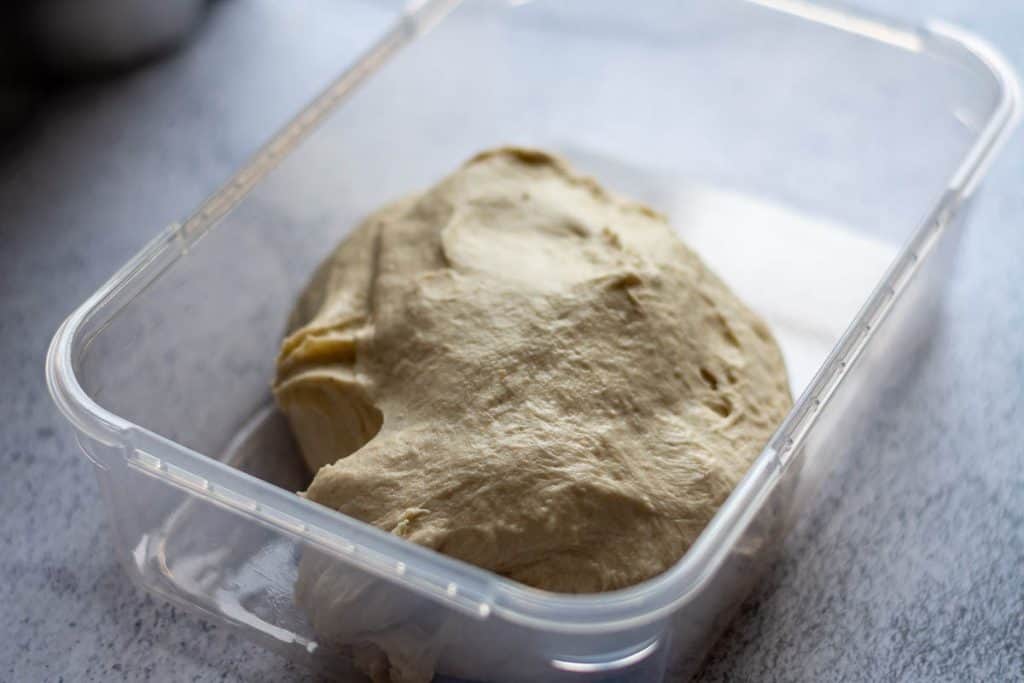 Mixed dough scooped into a plastic container.