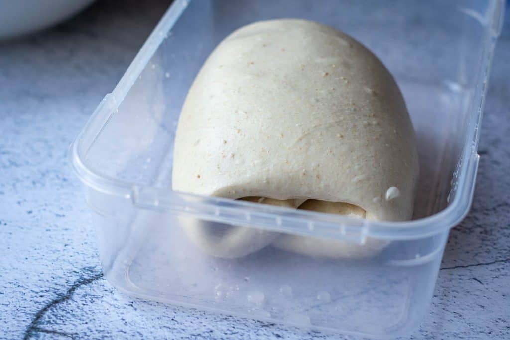 Coil folded sourdough in a plastic container.