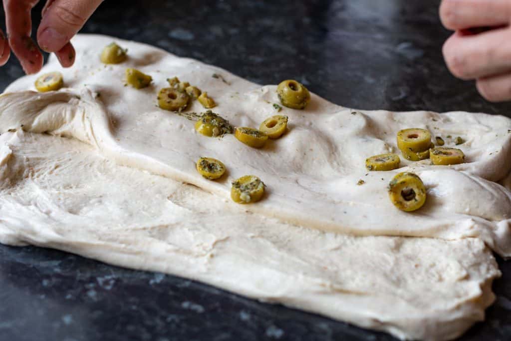 Laminating roasted garlic green olives into sourdough.