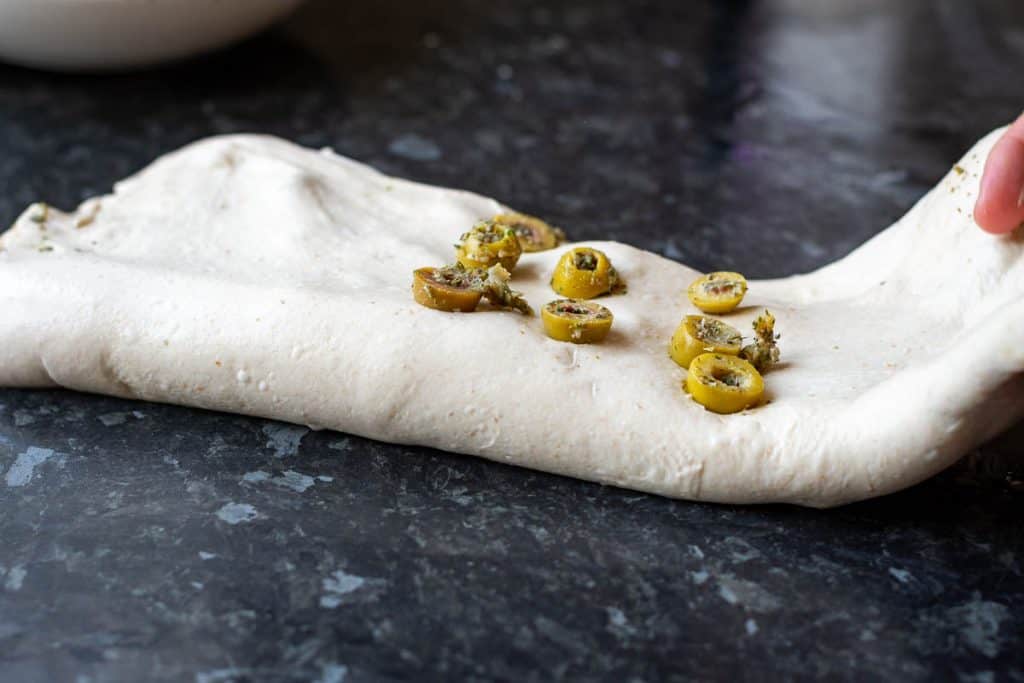 Laminating roasted garlic green olives into sourdough.