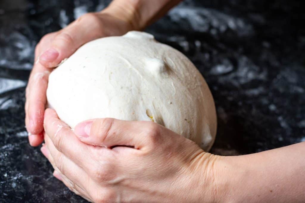 Creating surface tention by dragging a ball of sourdough against the work surface.