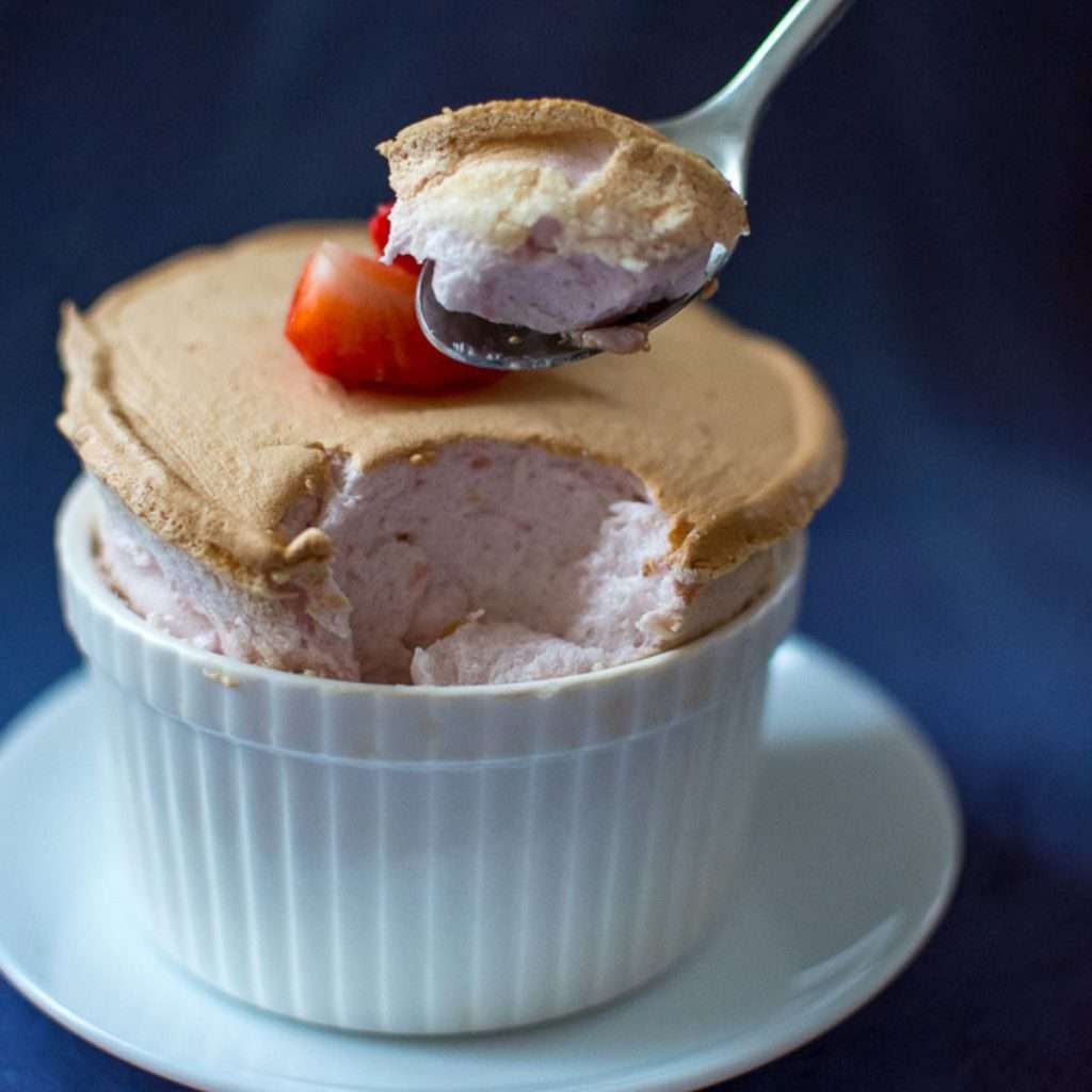 A spoonful of strawberry souffle being picked up.