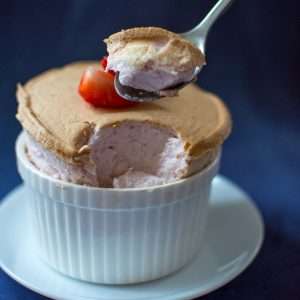 A spoonful of strawberry souffle being picked up.