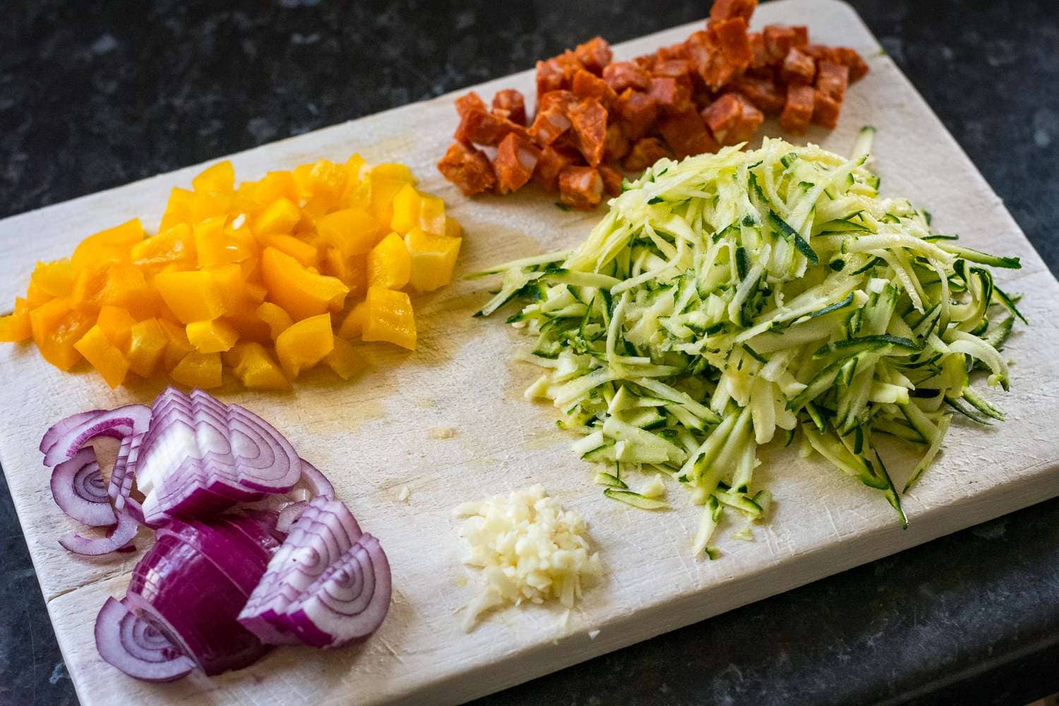 Vegetables for Huevos Rancheros on a wooden chopping board.