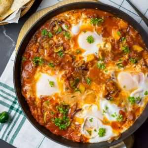 Huevos rancheros with chorizo in a large frying pan.