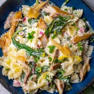 Creamy smoked mackerel pasta in a shallow blue bowl garnished with chives.