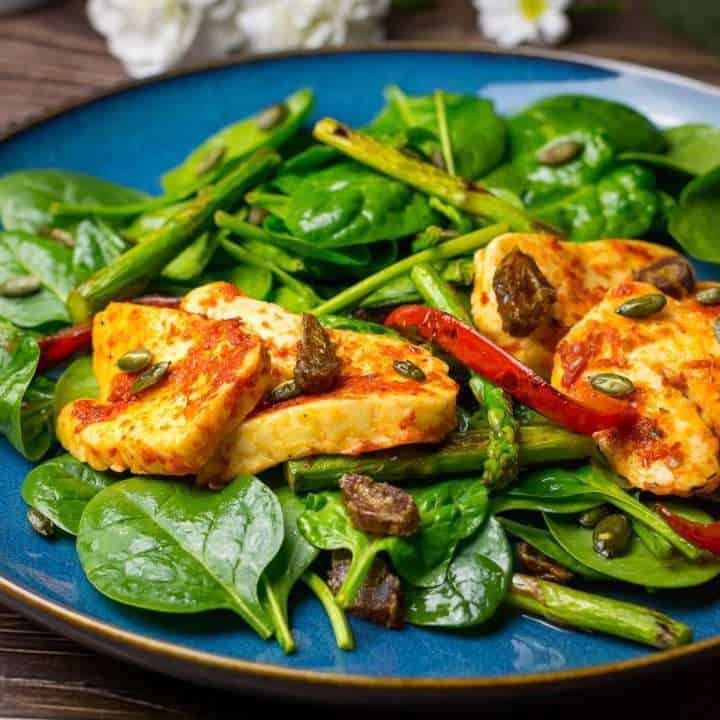 Spicy Halloumi Salad with spinach and asparagus on a large blue plate.