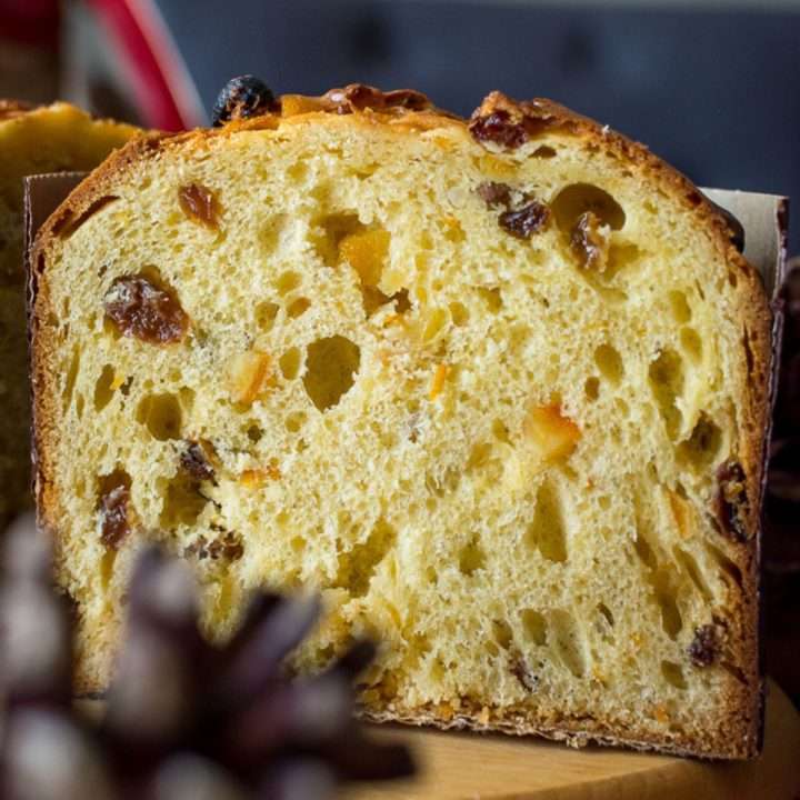 Half of sourdough panettone on a wooden board showing off airy crumb and domed top.