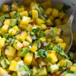 Mango and avocado salsa for salmon in a bowl with a spoon.