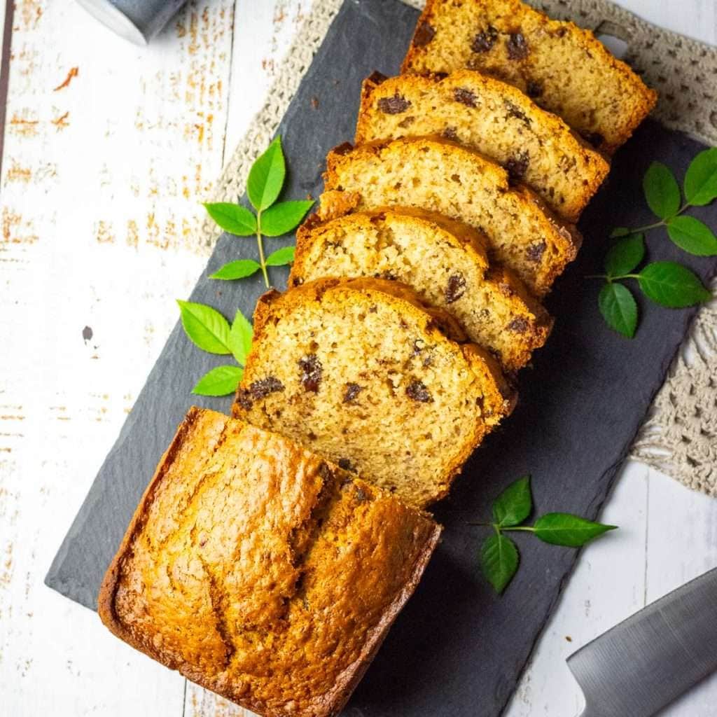 Sliced Sourdough Discard Banana Bread on a black slate board on a white table.