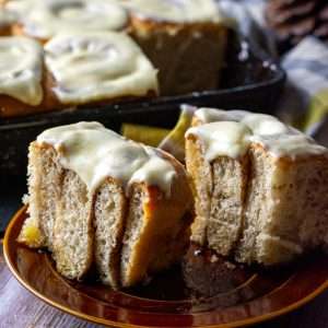 Sourdough Cinnamon Roll cut in half on a brown plate.