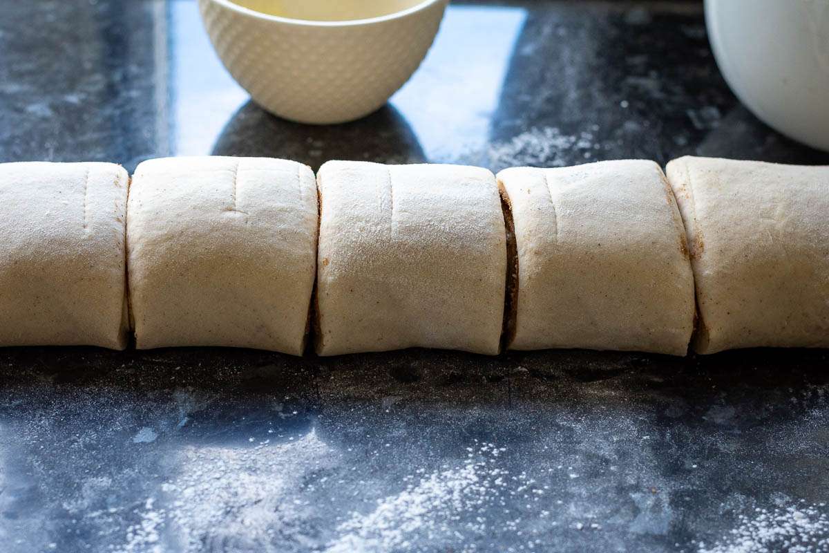 A tightly rolled sourdough cinnamon log cut into buns.