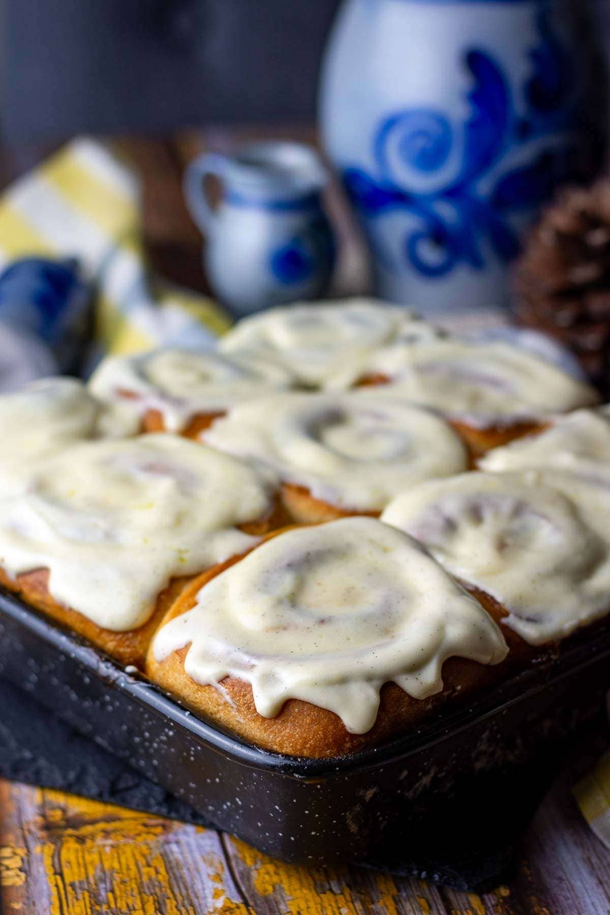 Sourdough Cinnamon Rolls with Cream Cheese Frosting on top on a wooden table.