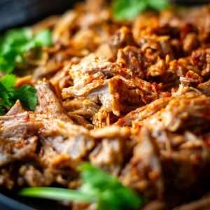 Slow cooked bbq pulled pork on a black plate.