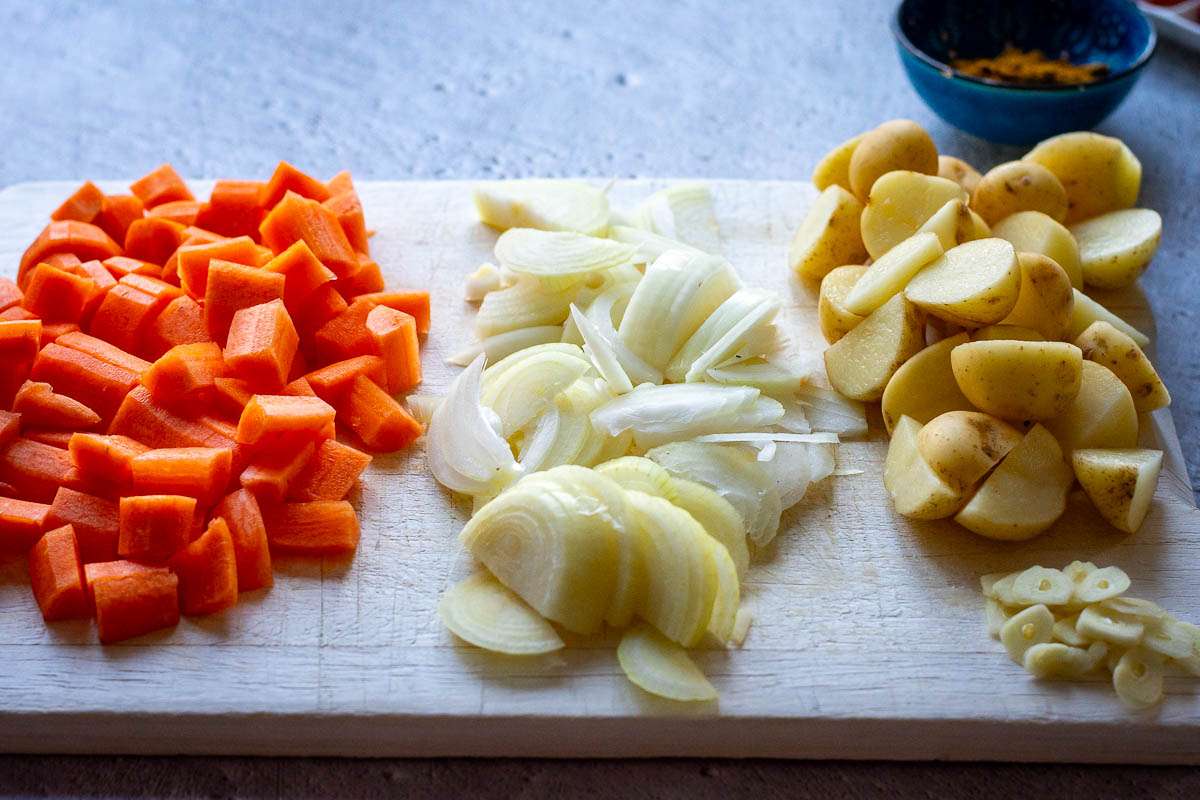 Chopped vegetables on a large wooden chopping board.