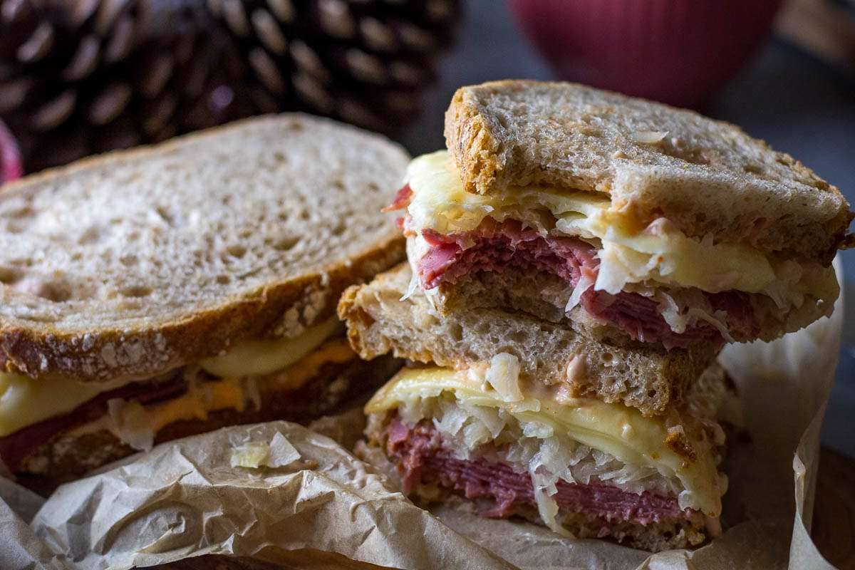Two halves of pastrami on rye sandwich stcked on top of each other.