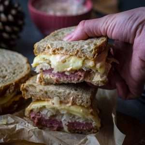 Two halves of pastrami on rye sandwich stcked on top of each other.