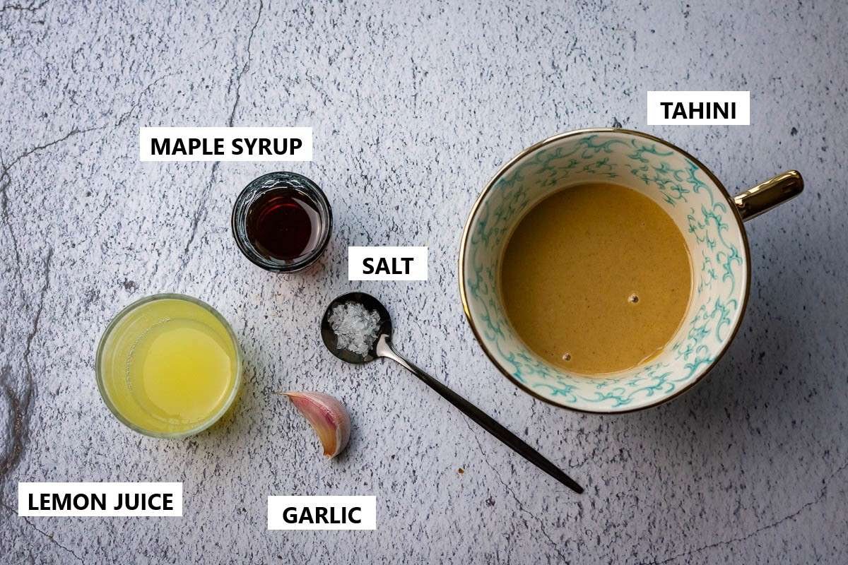 Ingredients for Maple Tahini Salad Dressing on a grey surface.