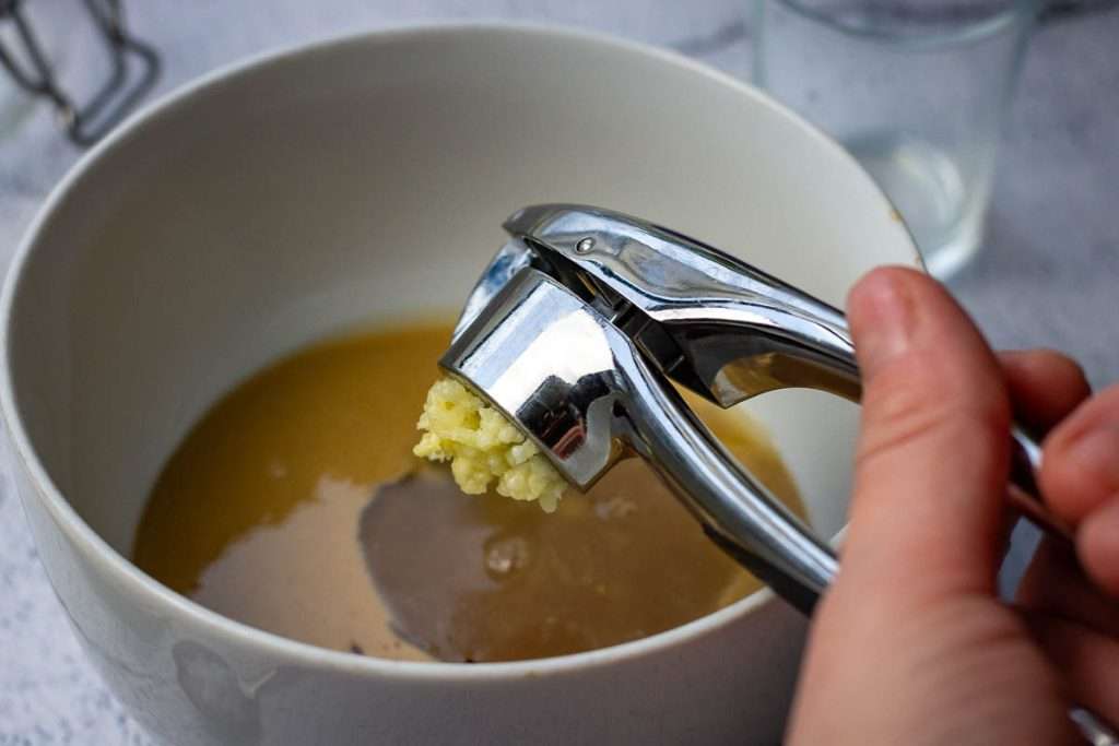 Adding garlic into the maple tahini dressing.