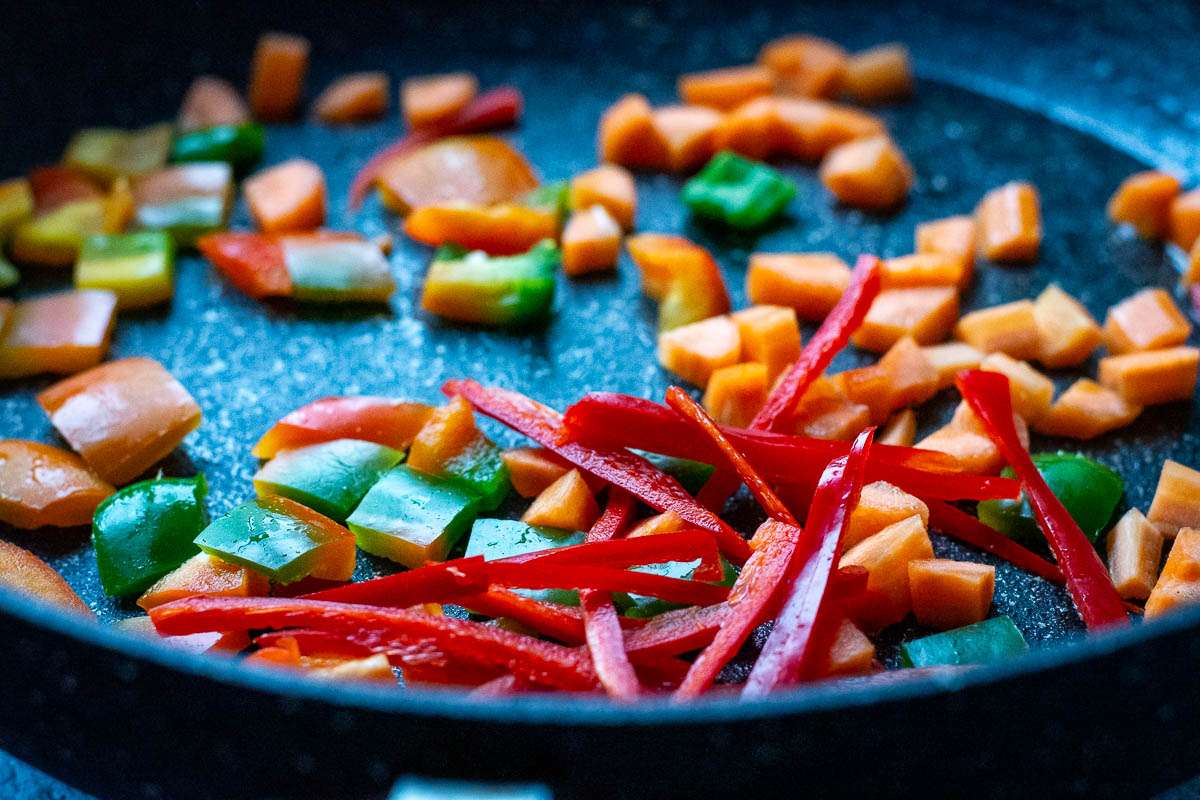 Stir frying carrots, chilli and bell peppers.