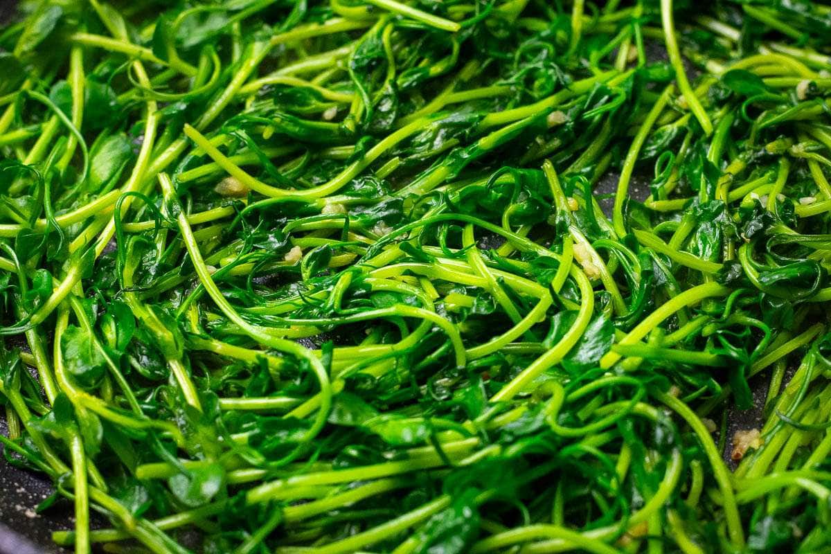 Chinese Pea Shoots with garlic in a large pan.
