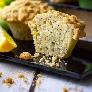 Half of the sourdough lemon poppy seed muffin on a black serving board on a white wooden table.