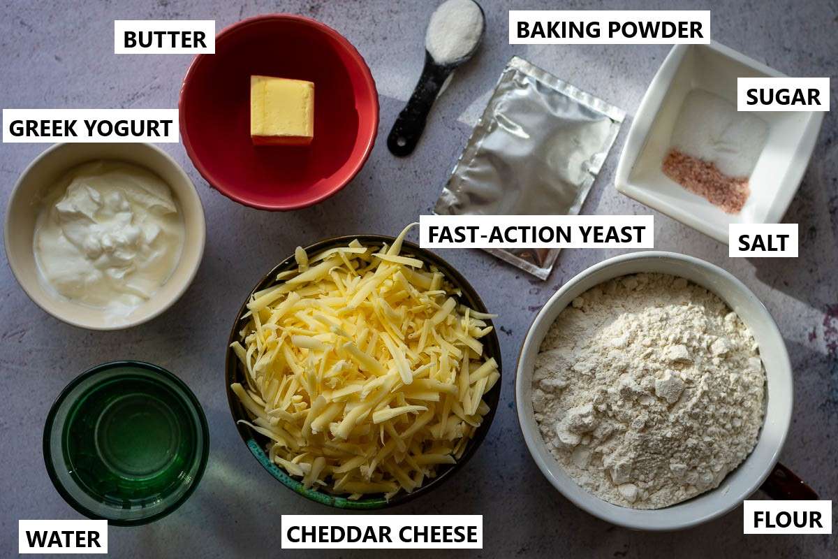 Ingredients for garlic cheese naan on a light grey surface.