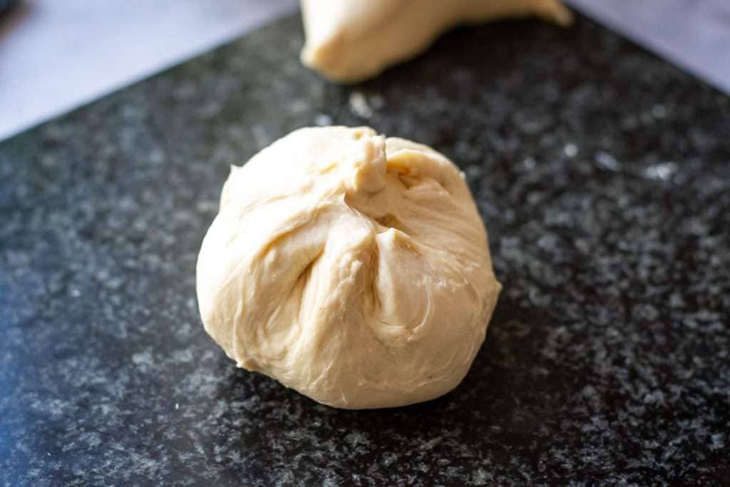Cheese fullly encased into the naan dough on a marbel surface.