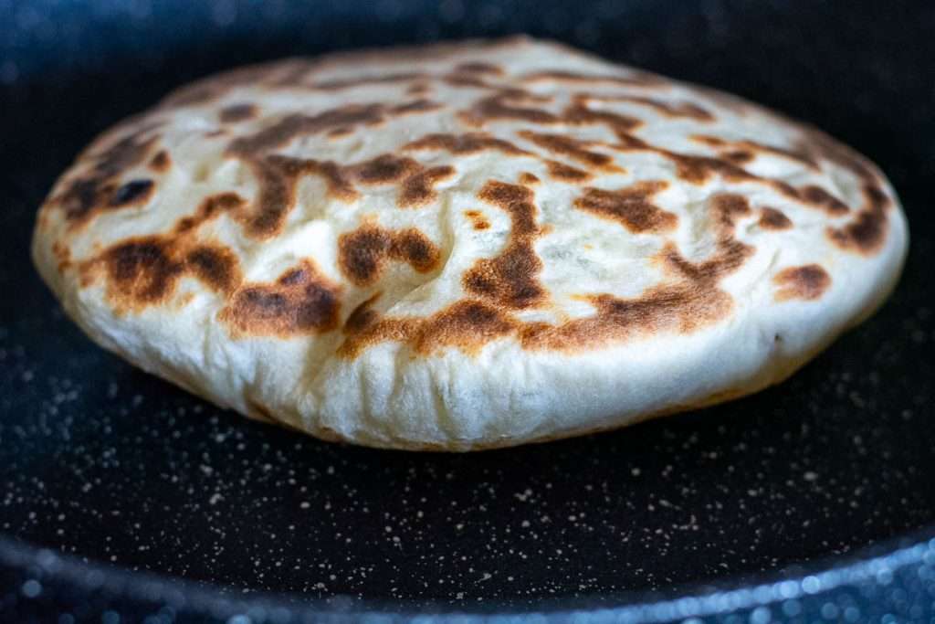 Cheese naan frying on the second side.