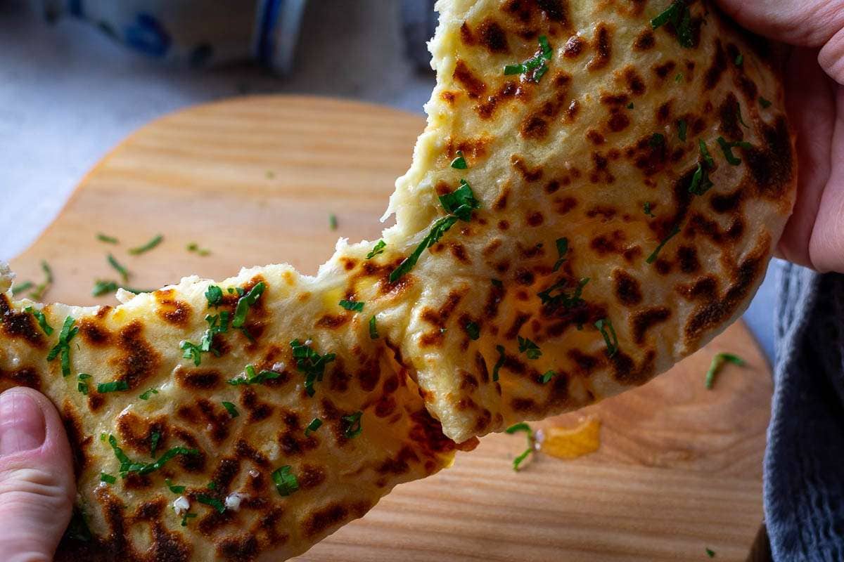 Garlic Cheese Naan being torn in half.