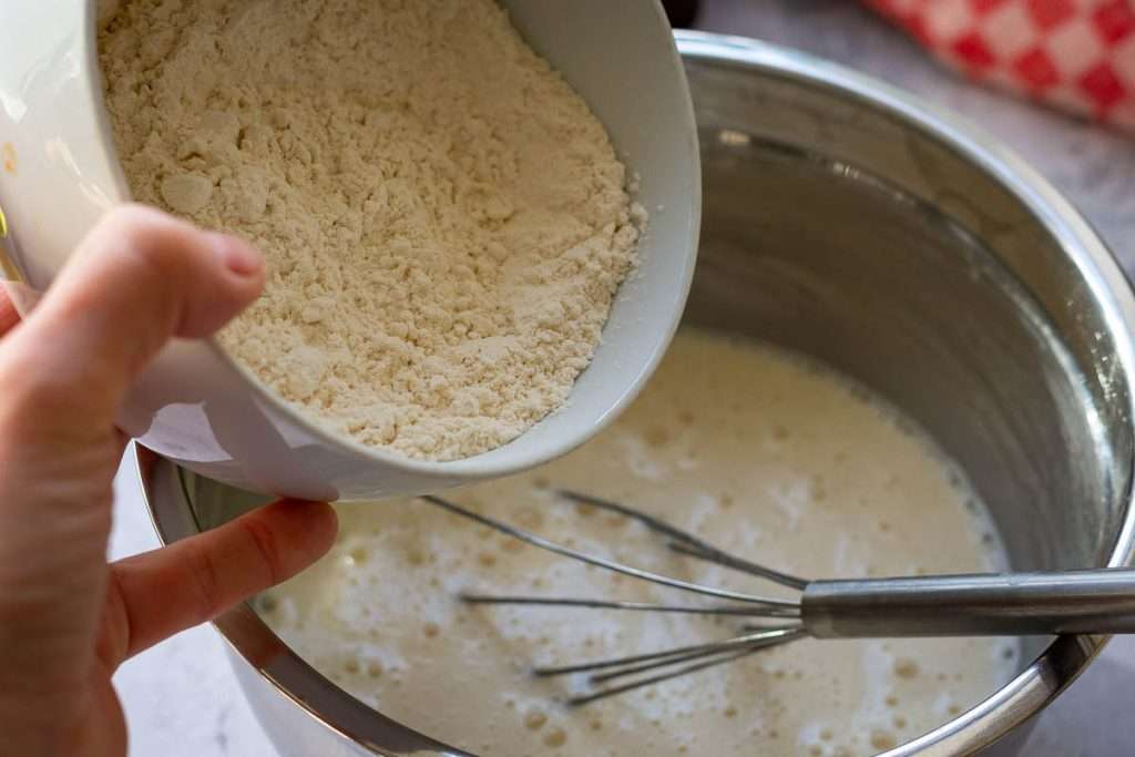 Adding dry ingredients into the wet ingredients to make the sourdough cupcake batter.