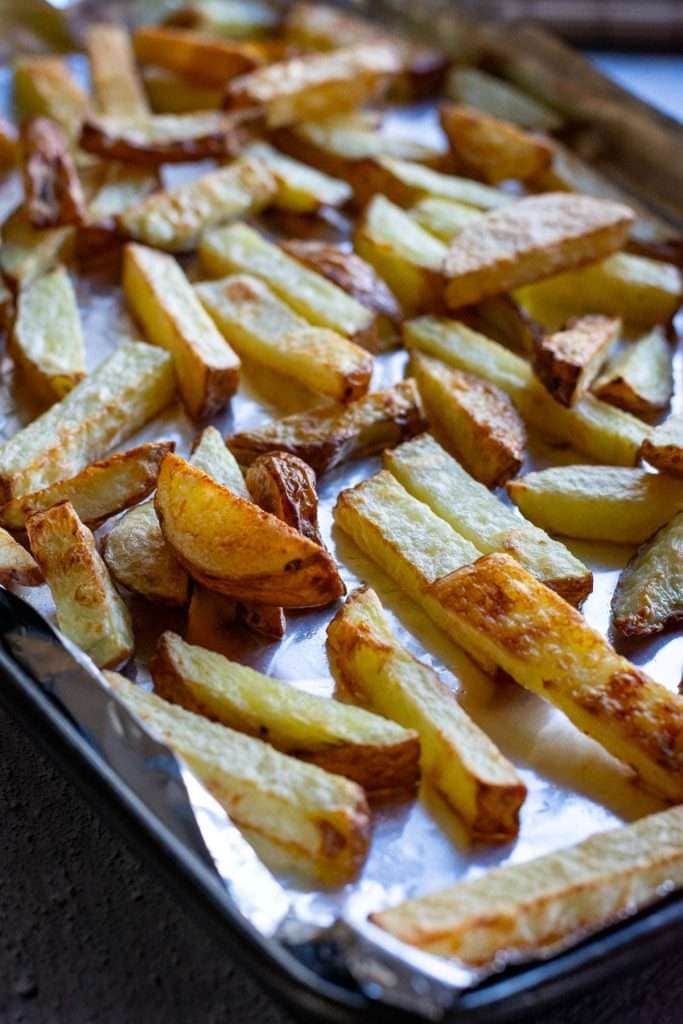 Cooked potato chips on a baking tray.