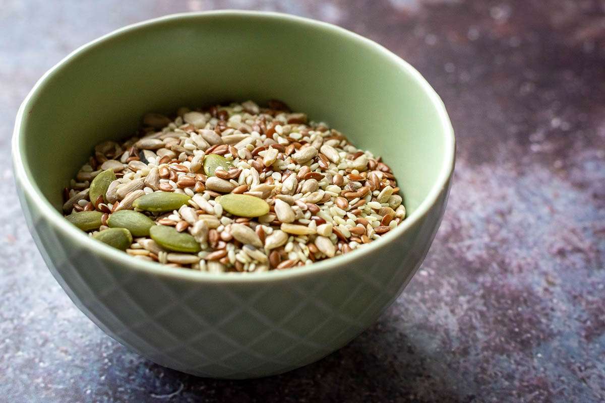 Mixed seeds in a small pale green bowl.