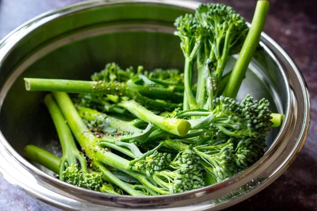 Washed tenderstem broccoli in a metal bowl.