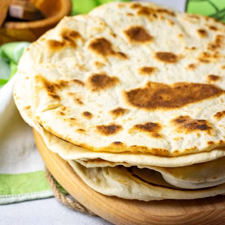A stack of sourdough torillas on a wooden board.