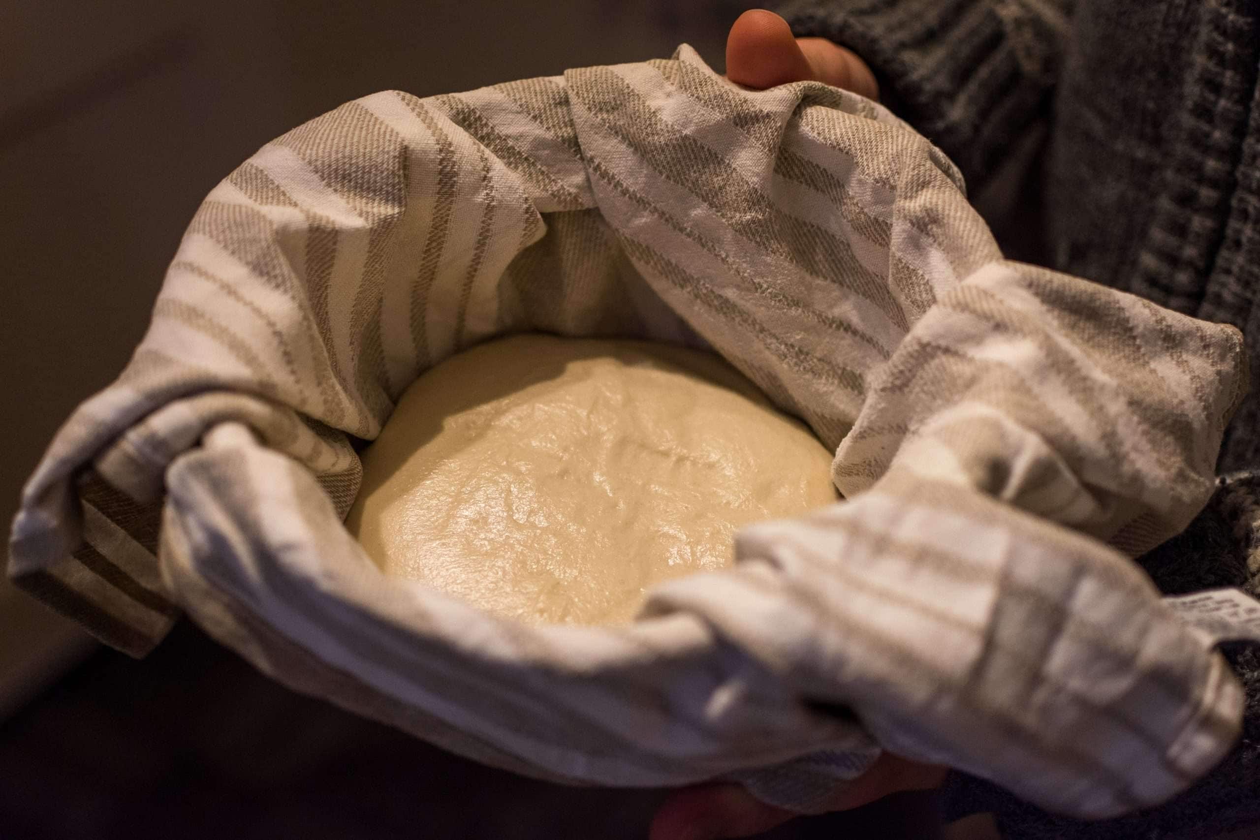 Sourdough in a tea-towel lined metal mixing bowl.
