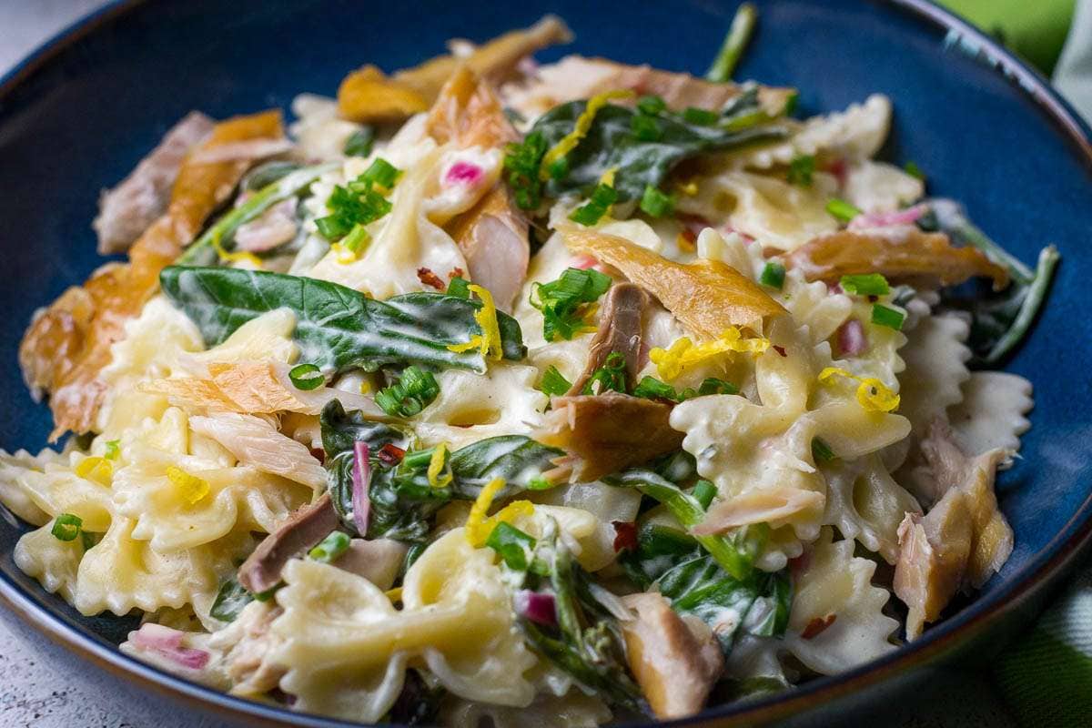 Creamy mackerel pasta in a blue bowl on a white table.