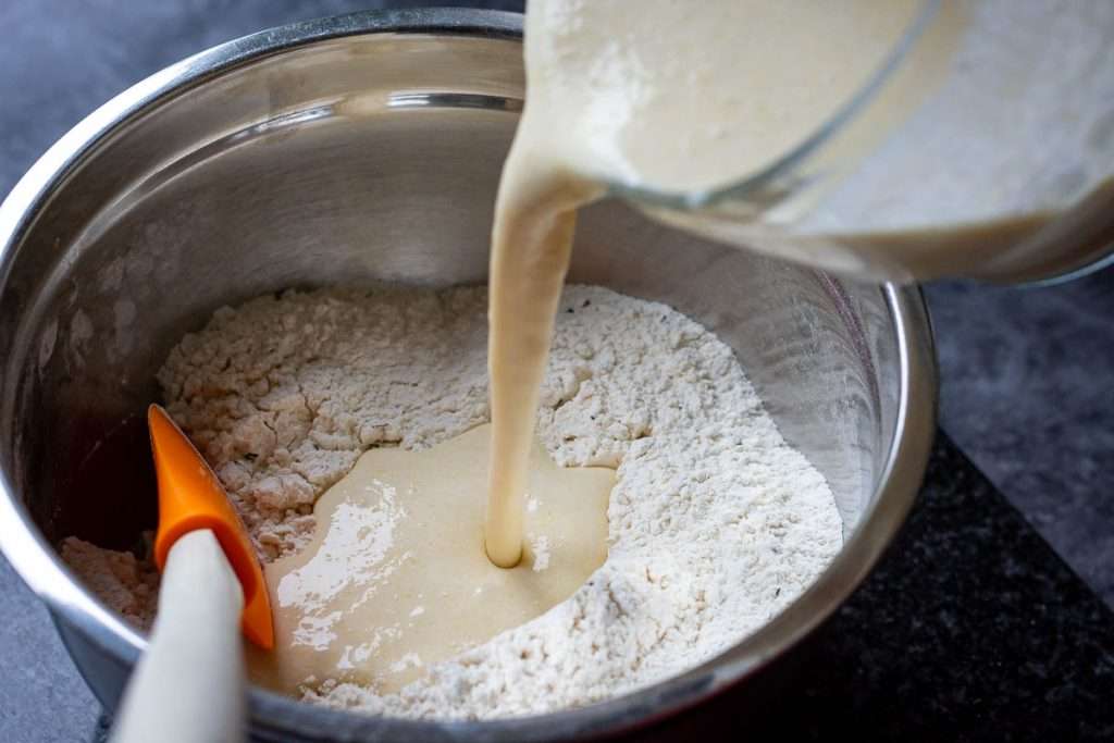 Pouring wet ingredients into dry ingredients.