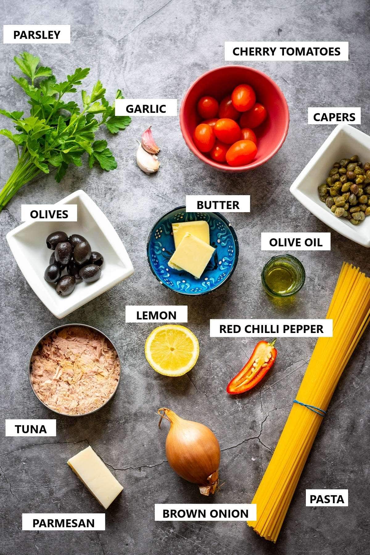 Ingredients for Tuna Pasta with olives on a grey surface.