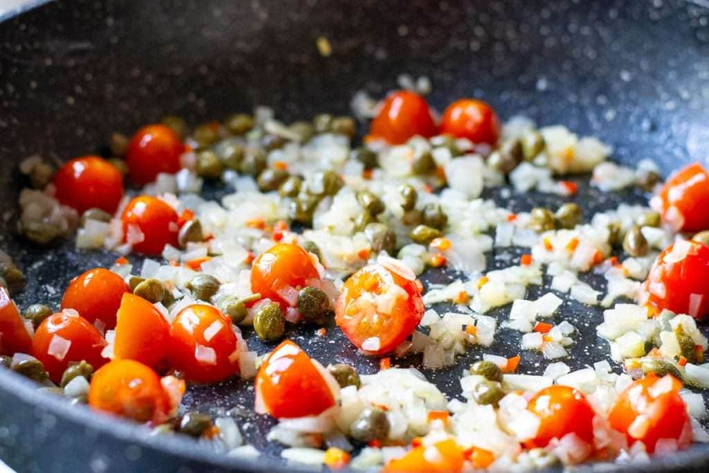 Cherry tomatoes added to the pan with sauteed onions and garlic.
