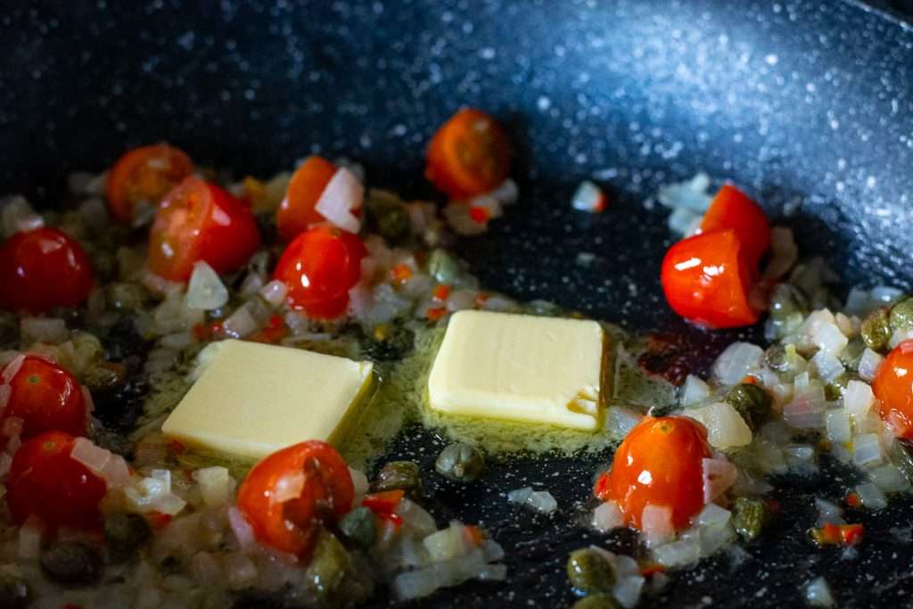 Butter melting in the onion and cherry tomato pan.