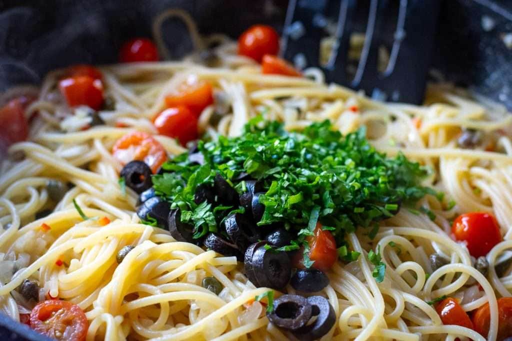 Olives and parsley on top of the cooked pasta.