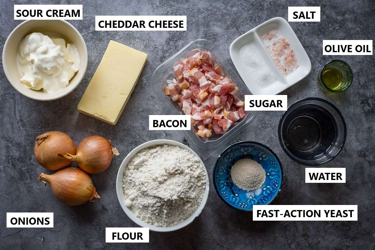 Ingredients for Flammkuchen pizza on a dark gray surface.
