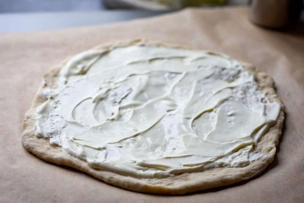 Sour cream spread on the pizza base.