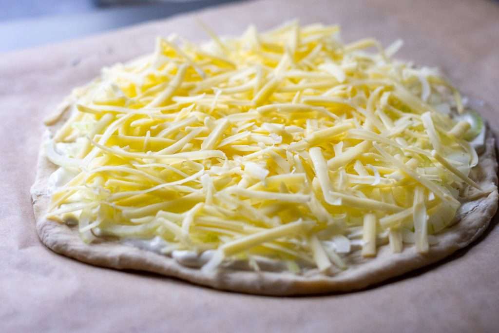 Grated cheese on top of the sour cream pizza base.