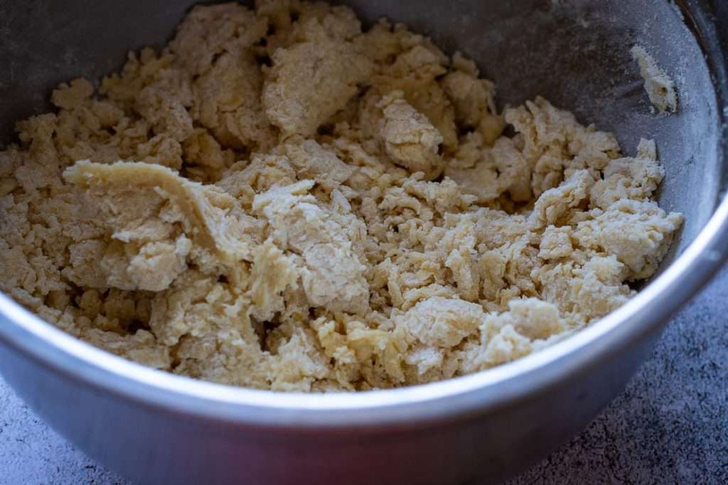 The cookie dough being mixed in a metal bowl.