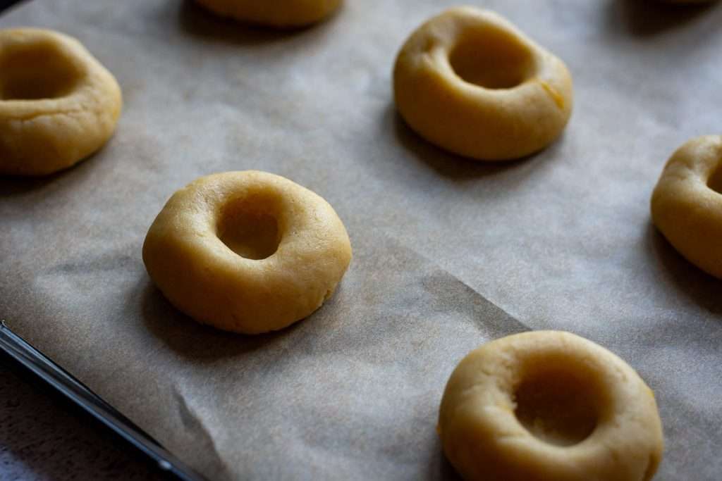 Lemon thumbprint cookies arranged on a baking sheet lined with parchment paper.